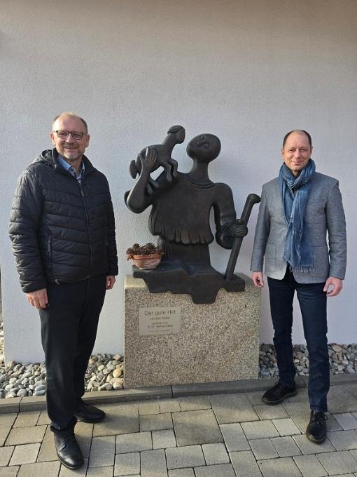 Der aktuelle Stiftungsvorstand, bestehend aus Peter Ehmann (li) und Volker Göbel (re), vor der Originalplastik „Der gute Hirt“ welche von Max Walter aus Werneck gestaltet wurde und vor dem Eingangsbereich der Tagespflege „Der gute Hirte“ der Caritas in Ebermannstadt steht.