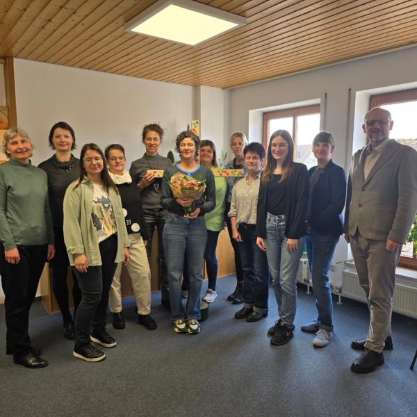 Heike Fuchs mit Blumenstrauß im Kreis ihrer Kolleginnen und Peter Ehmann