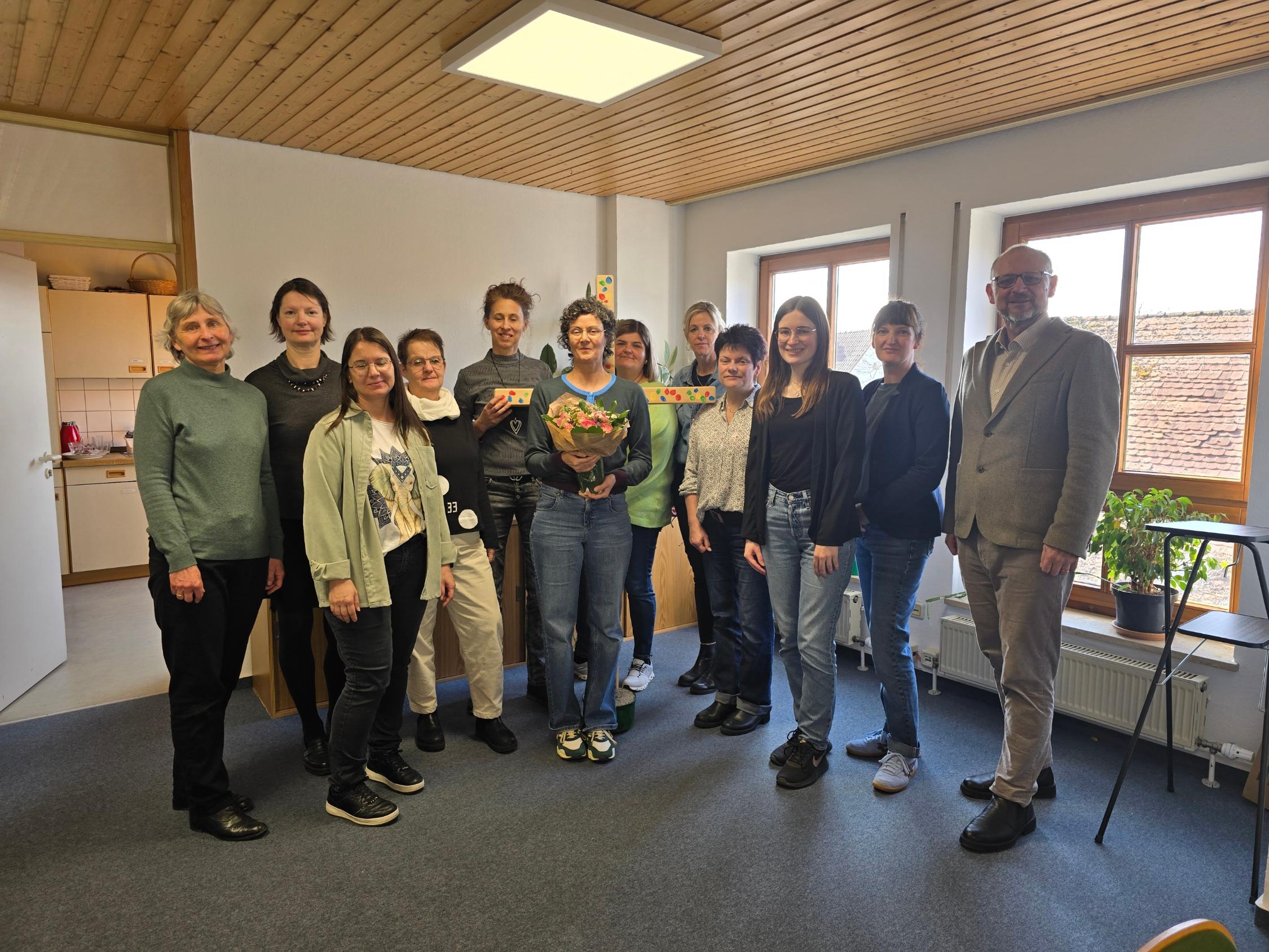 Heike Fuchs mit Blumenstrauß im Kreis ihrer Kolleginnen und Peter Ehmann